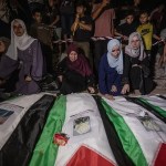 Personas en duelo encienden velas durante un funeral colectivo y una vigilia por 105 palestinos, cerca de los escombros del edificio Al Tajj en la ciudad de Gaza