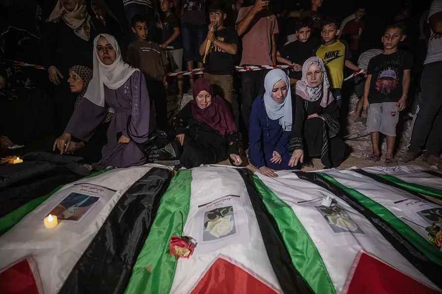 Personas en duelo encienden velas durante un funeral colectivo y una vigilia por 105 palestinos, cerca de los escombros del edificio Al Tajj en la ciudad de Gaza