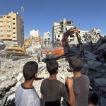 Unos niños gazatíes observan el derrumbe de un edificio residencial de seis plantas en la Franja de Gaza.