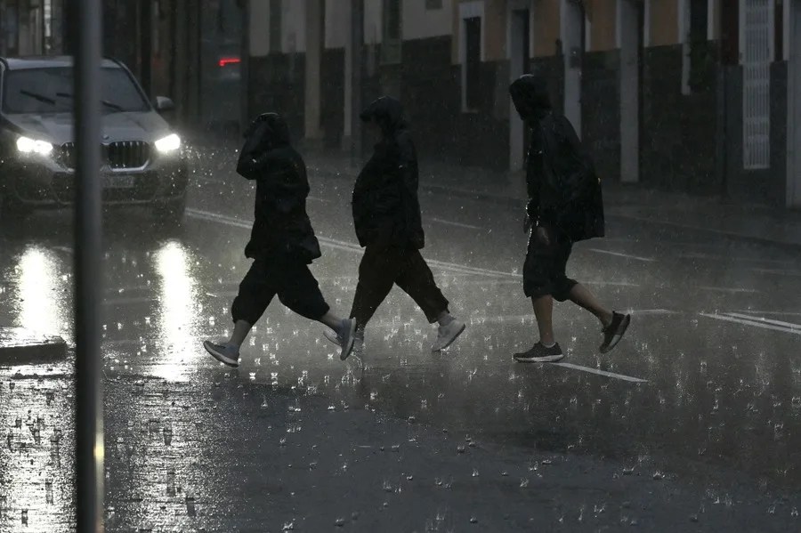 Varias personas caminan empapadas por una calle de Palma este lunes.