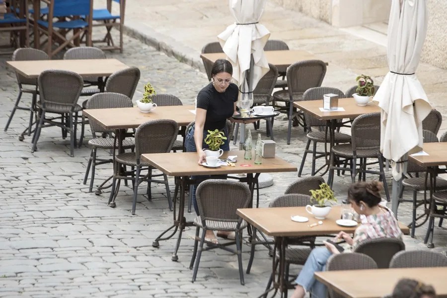 Una trabajadora recoge una mesa en la ciudad balear de Mahón.