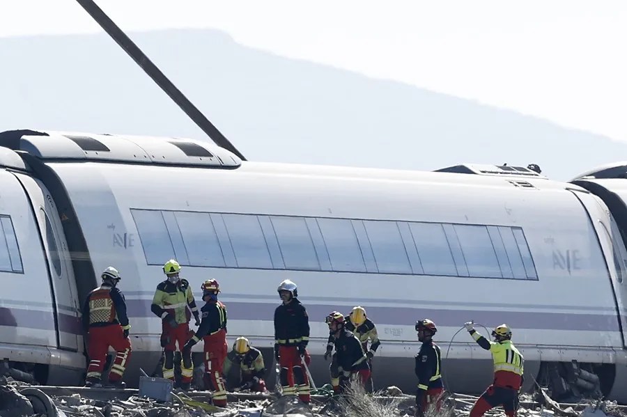 Efectivos de bomberos inspeccionan junto a los vagones del tren AVE que ha colisionado este miércoles con otro de Iryo