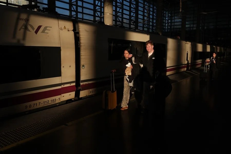 Varios pasajeros junto a un tren AVE en la estación de Atocha en Madrid.