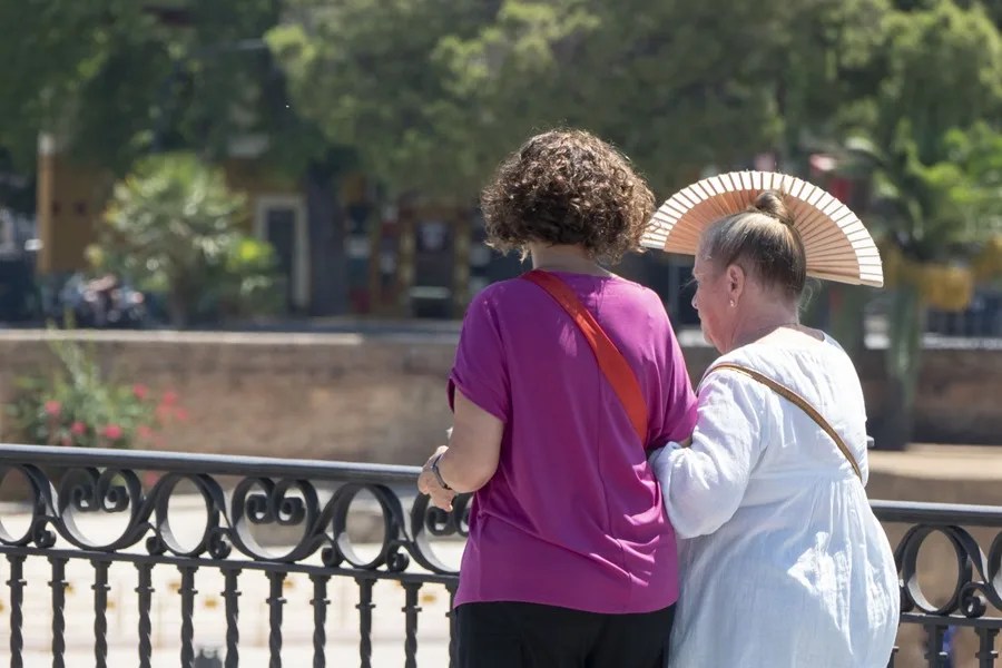 Dos mujeres pasean bajo el sol.