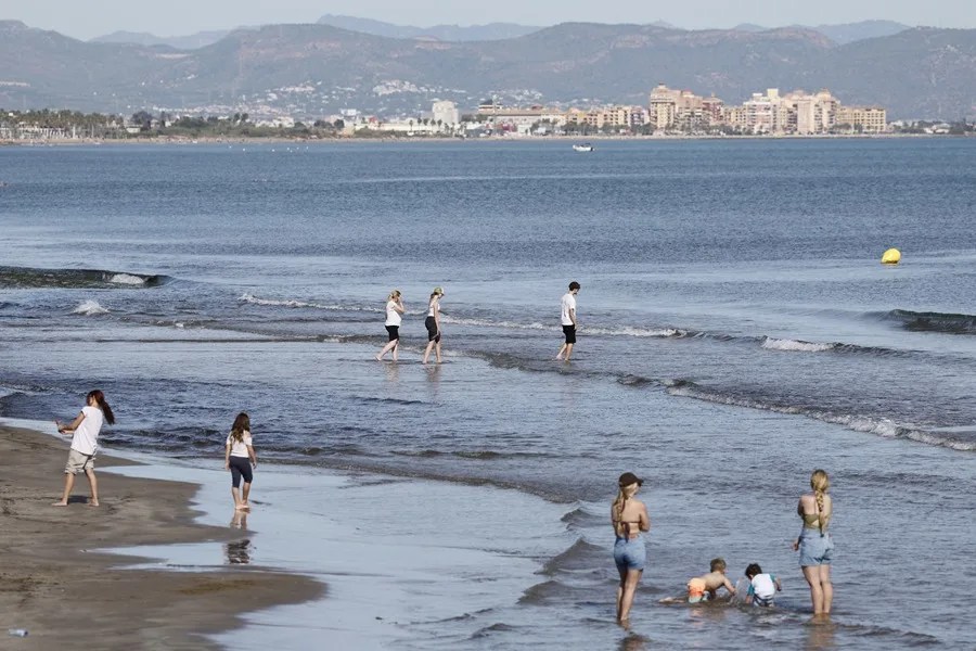 Varias personas disfrutan en la playa, de las agradables temperaturas que se registran este domingo en Valencia.