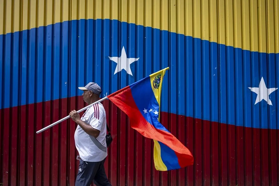Un hombre camina con la bandera de Venezuela.