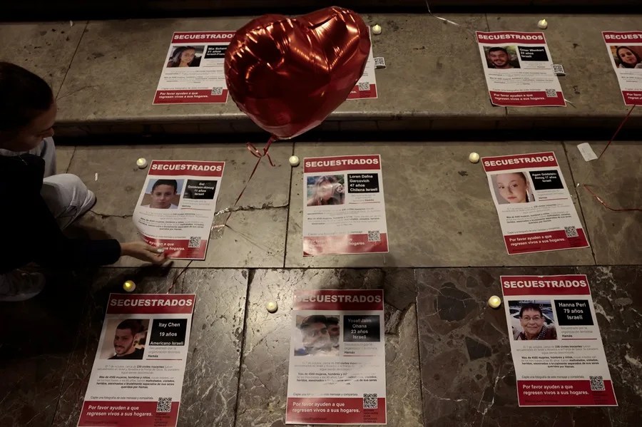 Una persona coloca unos carteles de rehenes capturados por Hamás en su ataque del pasado 7 de octubre.