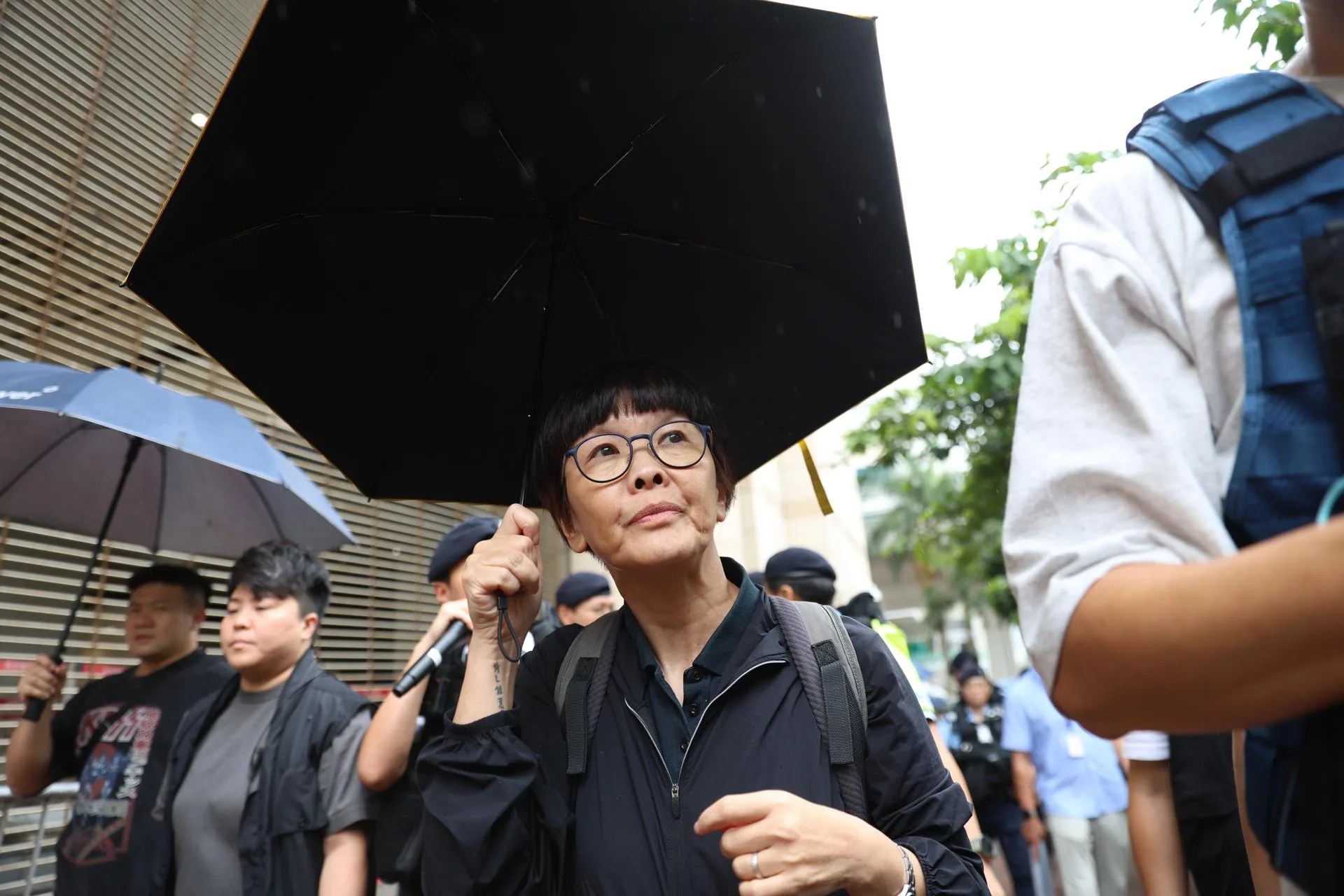 (FILE) Police officers escort former dentist and activist Lee Ying-chi (C), holding an umbrella, as she leaves the West Kowloon Law Courts Building after the verdict in Hong Kong, China, 21 August 2026. EFE/EPA/MAY JAMES