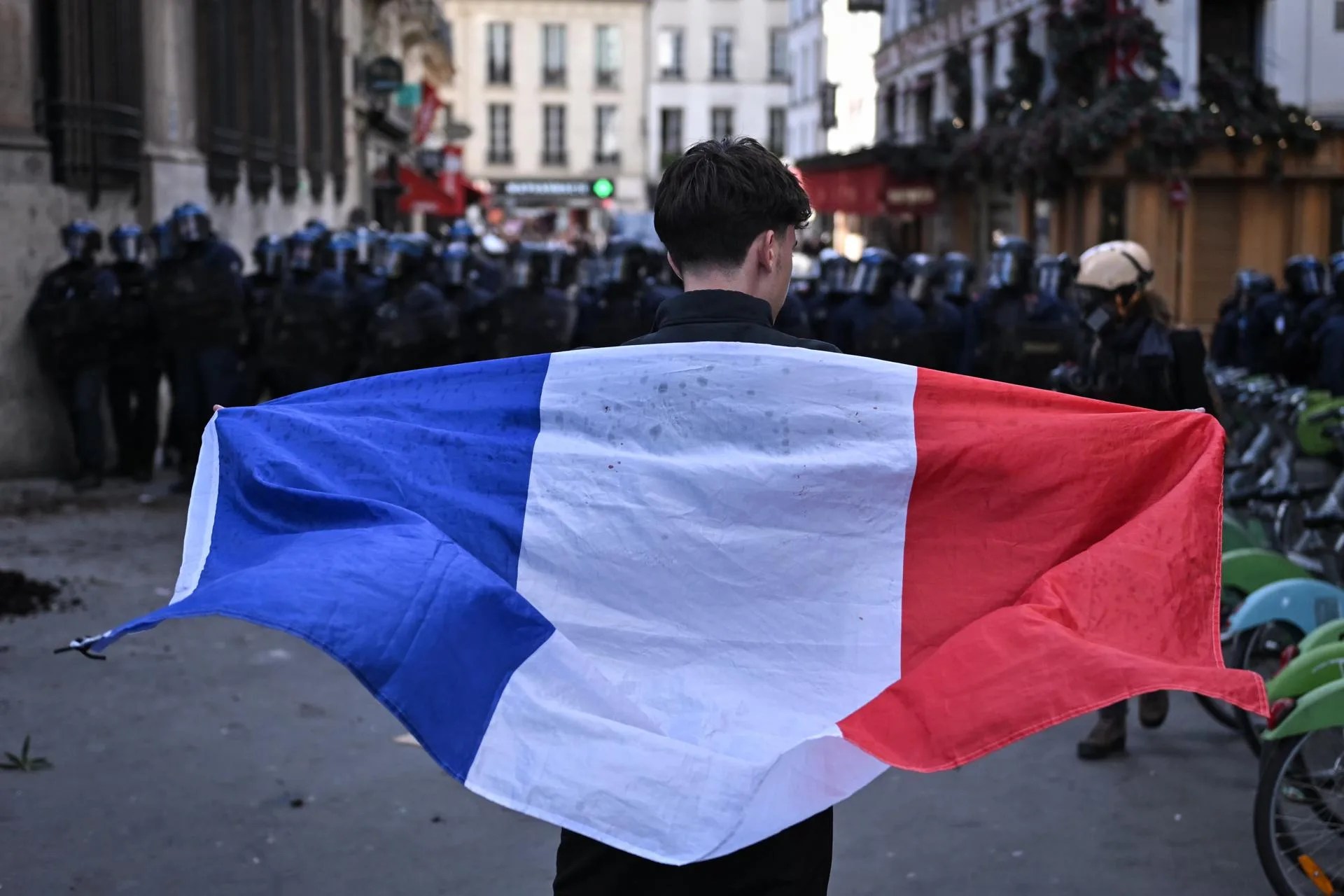 A protester holds the France national flag as clashes with riot police erupt at Bastille square during a demonstration over school conditions in Paris, France, 08 October 2026. EFE/EPA/FIRAS ABDULLAH