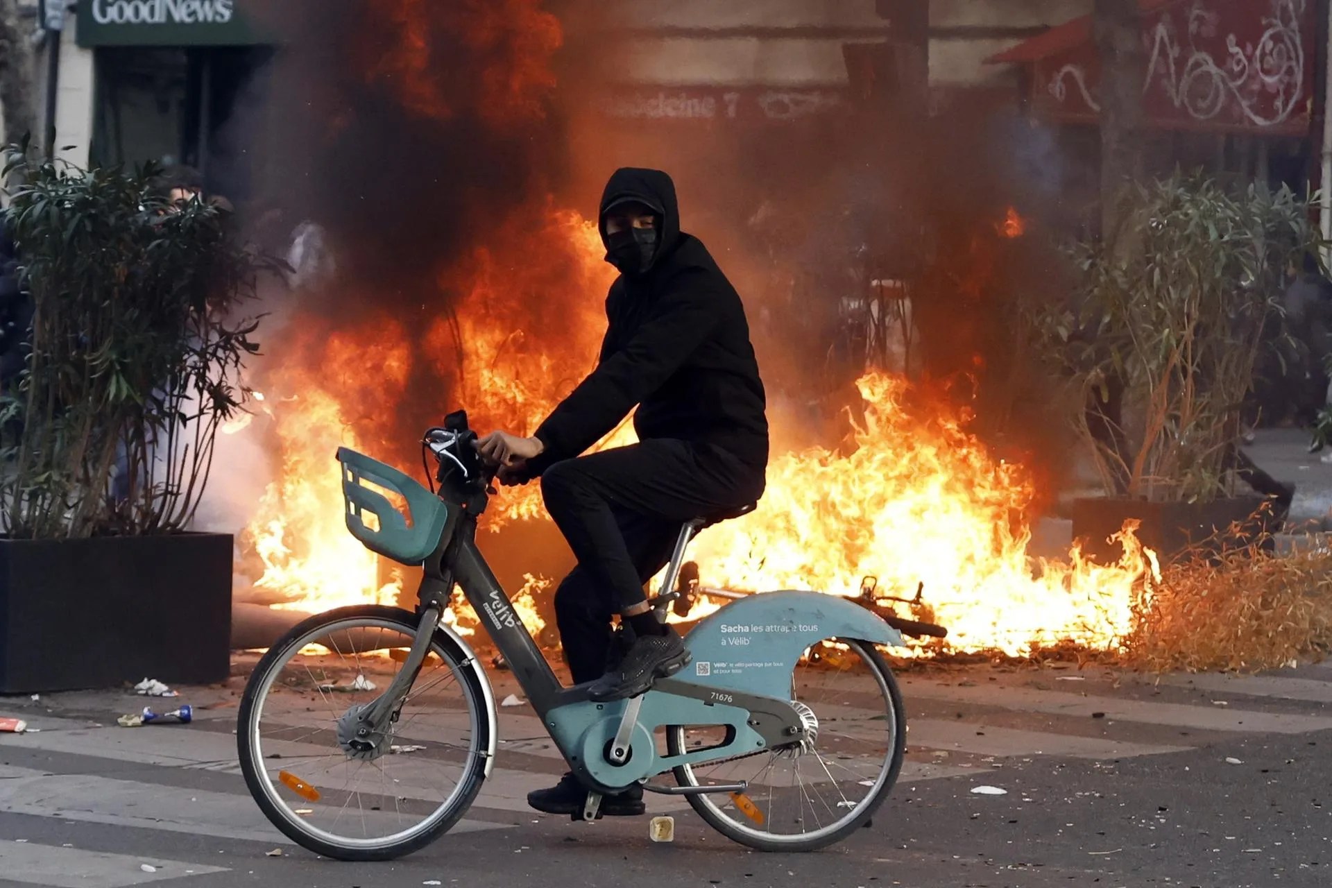 A man rides a bicycle past a fire in the street during a demonstration against rising living costs and cuts to public services in Paris, France, 17 October 2026. EFE-EPA/MOHAMMED BADRA