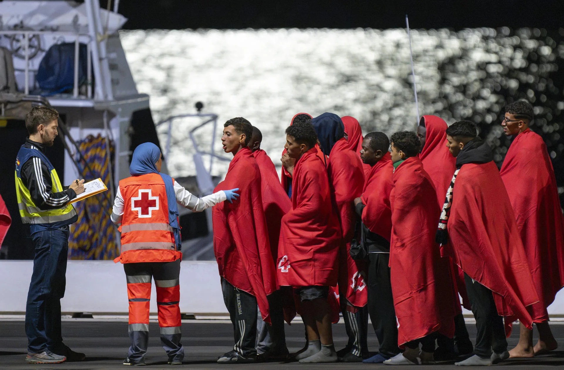 Migrantes se cubren con mantas de la Cruz Roja tras ser rescatados cuando navegaban en una embarcación en aguas próximas a Lanzarote