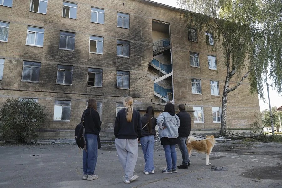 Unos niños de la zona permanecen cerca del lugar donde impactó un dron ruso contra un edificio escolar en una zona residencial de Kiev