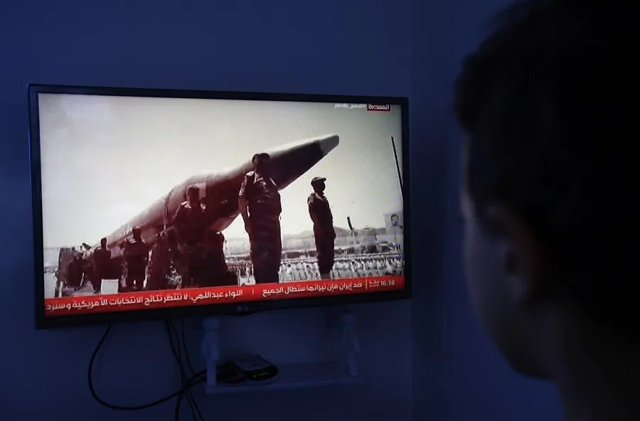 Una persona observa una emisión televisiva que muestra a combatientes hutíes junto a un misil, en el marco de los últimos acontecimientos del conflicto en Yemen