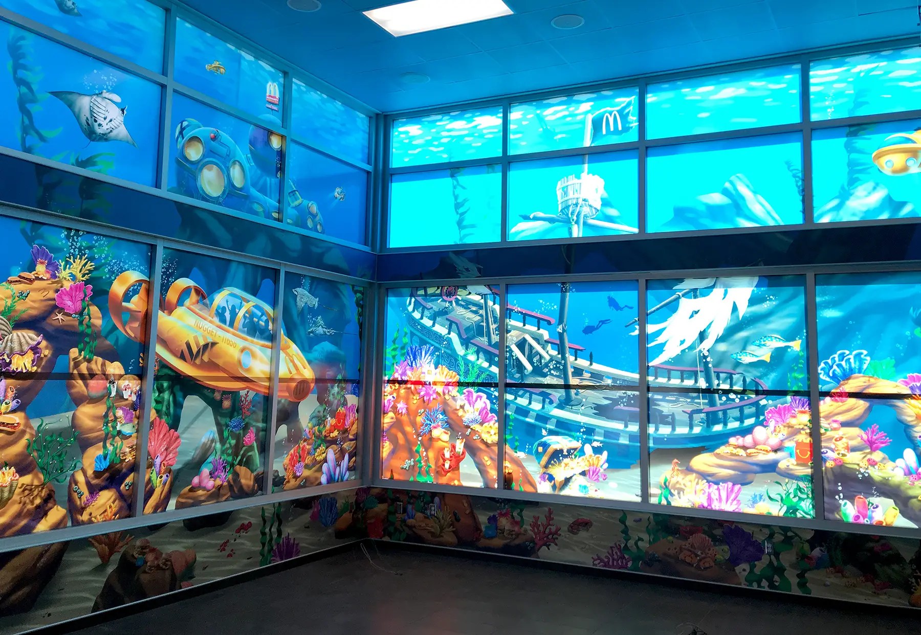 Underwater-themed vinyl wall mural installed at a McDonald’s play area, featuring custom submarine and coral reef illustrations — designed, printed, and installed by EG WRAPS.