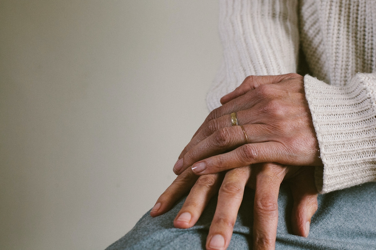 Sweater and sweatpants-clad individuals gently hold their hands together, likely lost in mindfulness meditation.