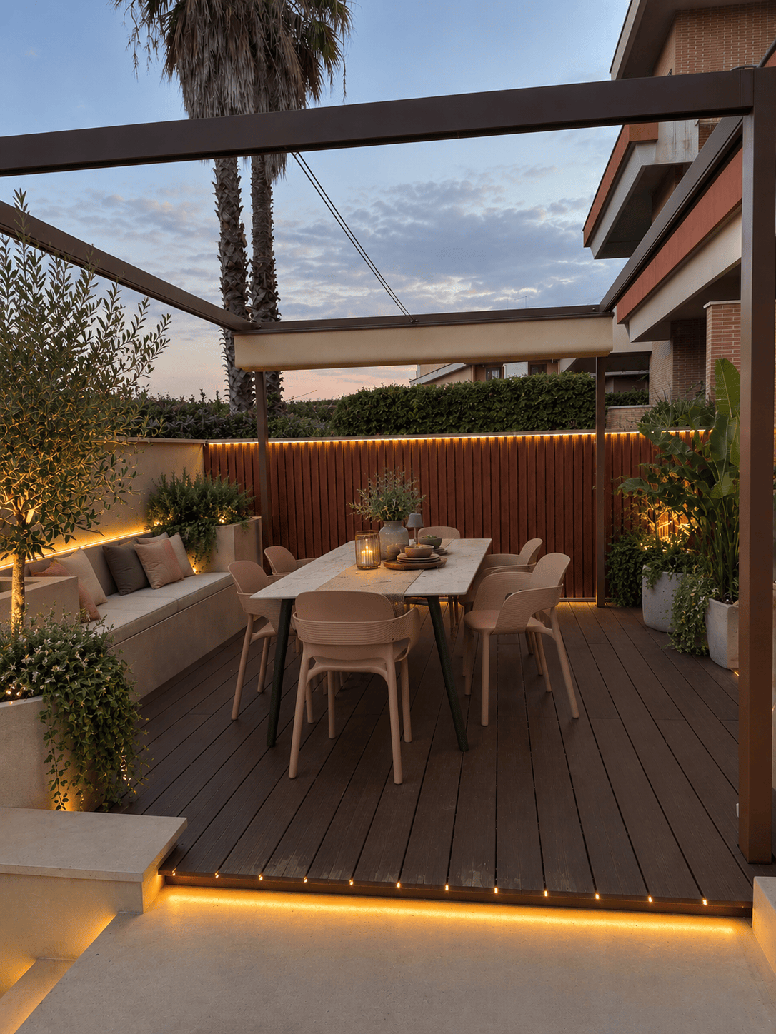 Outdoor all'Infernetto, Roma — il cortile a lavori finiti: pergola, decking, zona pranzo e luce integrata, al tramonto