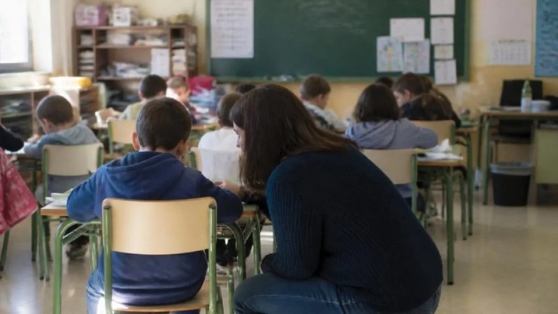 Aula de Primaria vista desde el fondo, con el docente atendiendo a un grupo