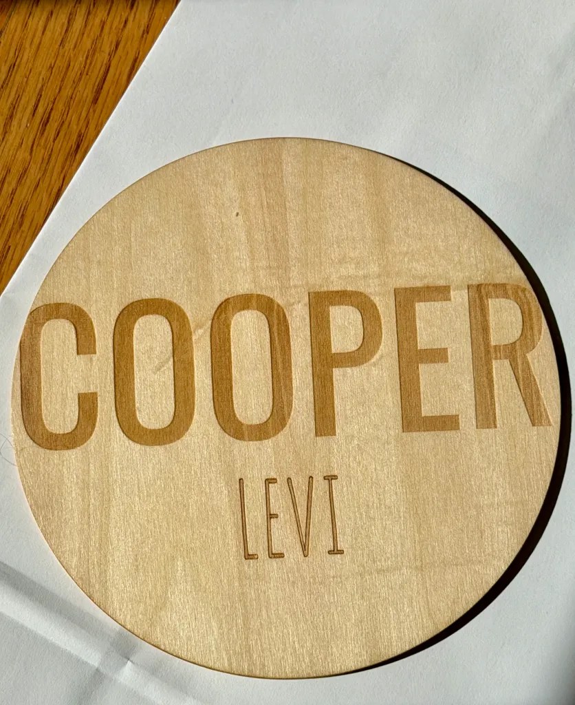 Round wooden baby birth announcement sign engraved with the name Cooper Levi
