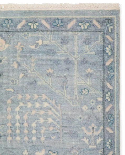 Soft blue and ivory hand-knotted wool rug with a subtle botanical pattern for a refined coastal bedroom