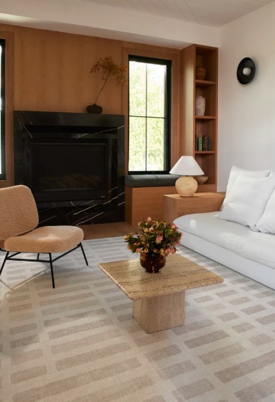 Refined living room with an ivory sofa, sculptural wood coffee table and oversized ivory-and-natural patterned rug.