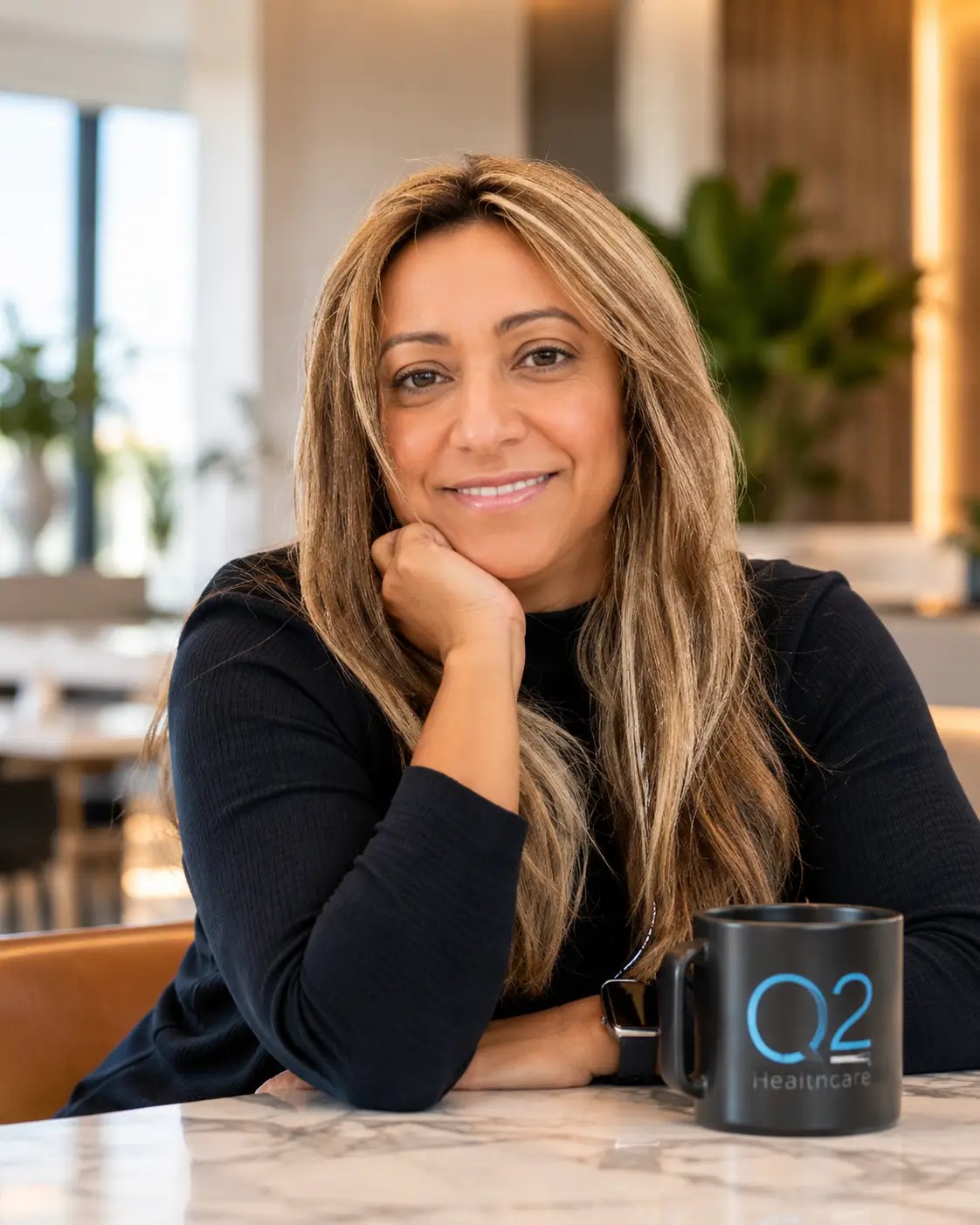 Karmen seated at a table with an O2 Healthcare mug