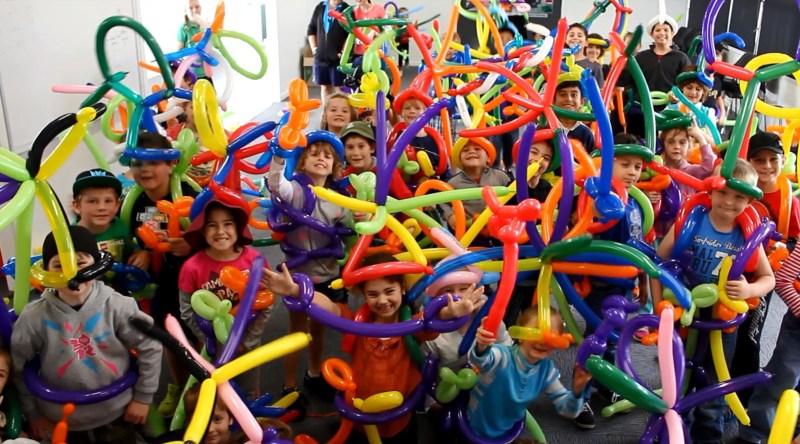 Children surrounded by brightly colored balloon sculptures they made