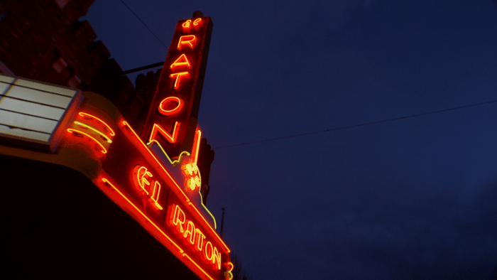 Neon sign for "El Raton" theater against a night sky.