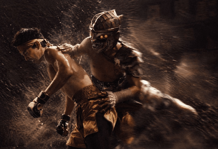 A shirtless man grapples with a warrior in armor with glowing eyes amidst a cloud of water, showcasing an intense fight scene.