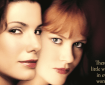 Close-up of the 4K UHD poster for "PRACTICAL MAGIC," featuring two women with dark and red hair, respectively, and the tagline "There's a little witch in every woman" at the bottom right.