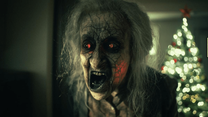 A close-up of a possessed character from "UNHOLY NIGHT" with a skeletal face, red glowing eyes, and long gray hair, set against a blurred Christmas tree in the background.