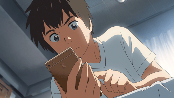 Animated close-up of a dark-haired teenager in a white shirt intently examining a brown smartphone indoors.