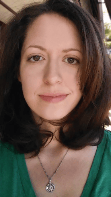 Close-up portrait of writer/director Katie Harbin with shoulder-length dark hair, wearing a green top and silver pendant necklace.