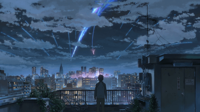 A silhouetted person watches bright blue and pink streaks descend over a glowing city from a rooftop at night.