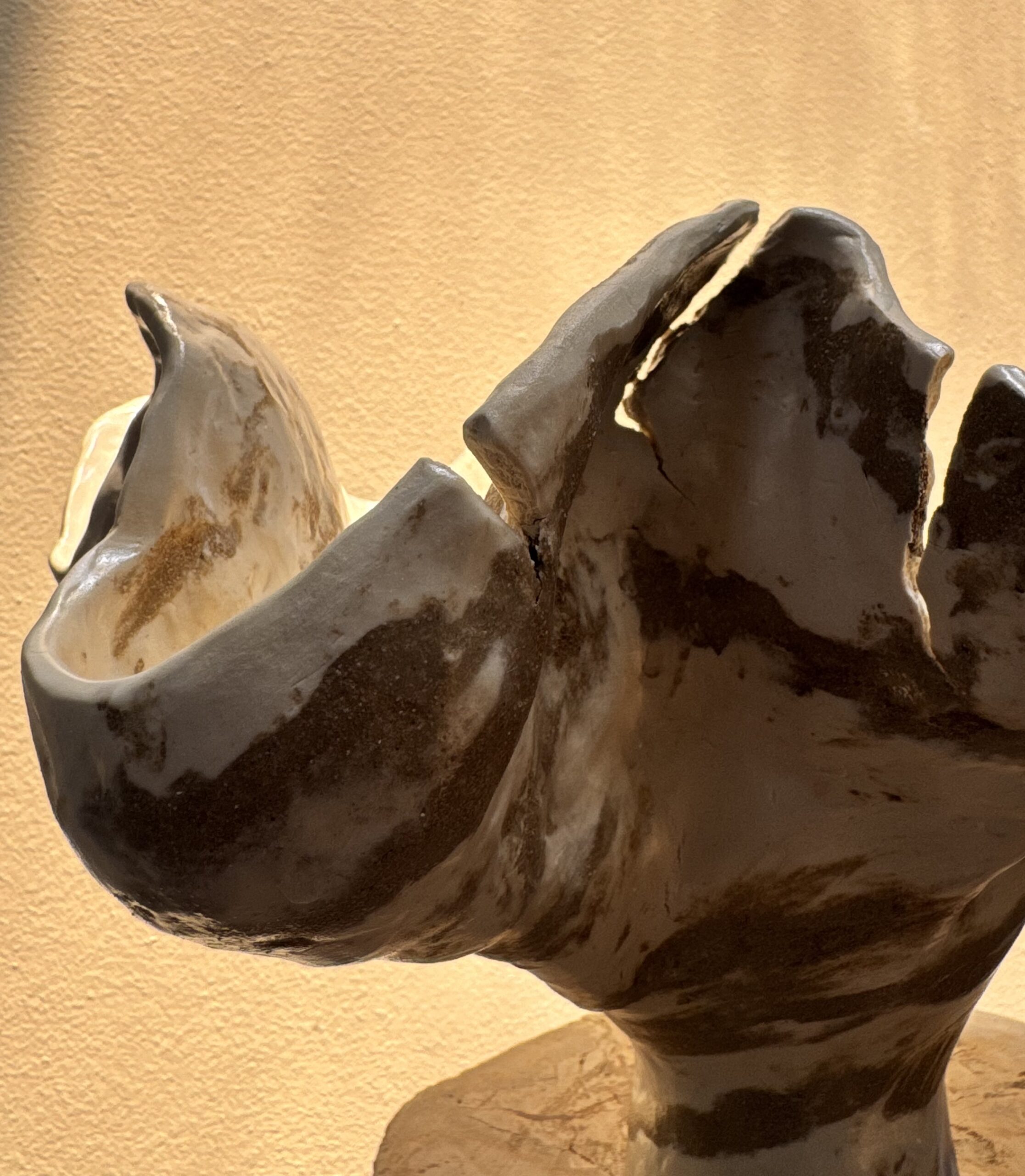 This large handcrafted ceramic vase features an organic, sculptural form inspired by mountains. The combination of brown and white color clays coiled in a spontaneous pattern gives a dynamic flow of color patterns and reminds you of a marble stone. Every curve carries the memory of touch - intentionally imperfect and alive. Showing detail.