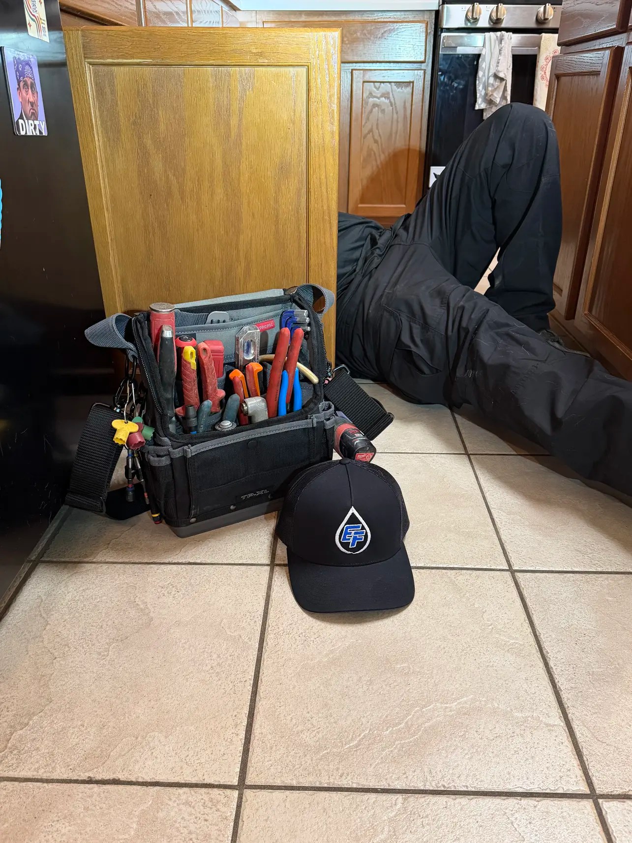 Elite Flow Services technician with tool bag performing under-sink repairs as an emergency plumber in Austin