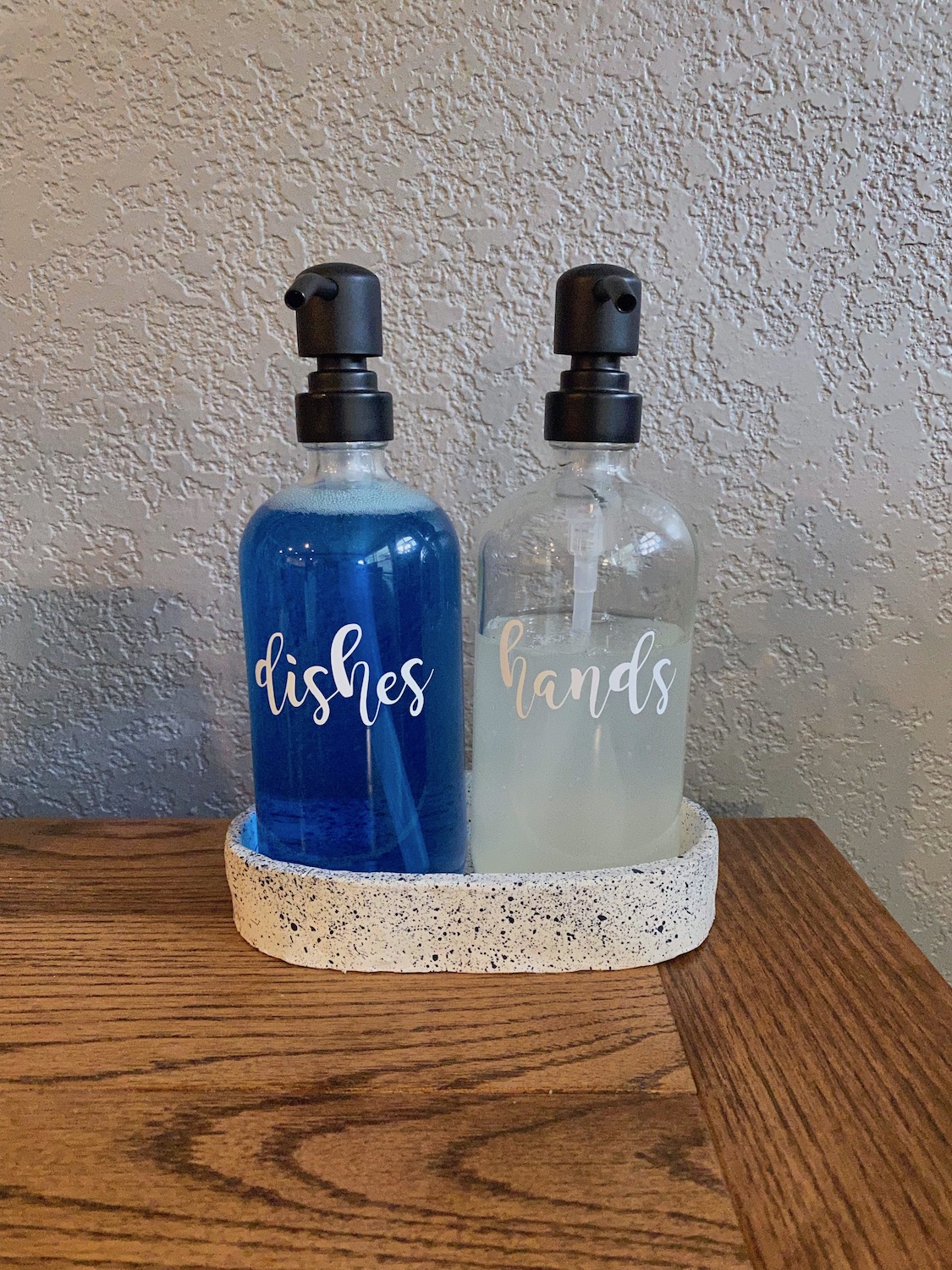 Two soap dispensers, one for dish soap, one for hand soap, sitting in a homemade clay dish.