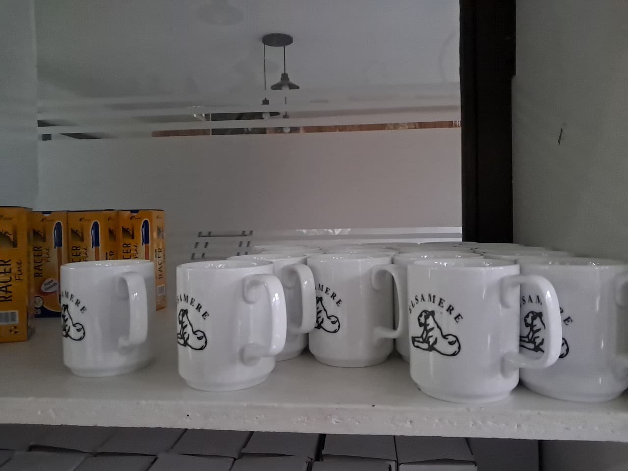 Set of white ceramic mugs branded with the Elsamere logo, displayed in the gift shop.