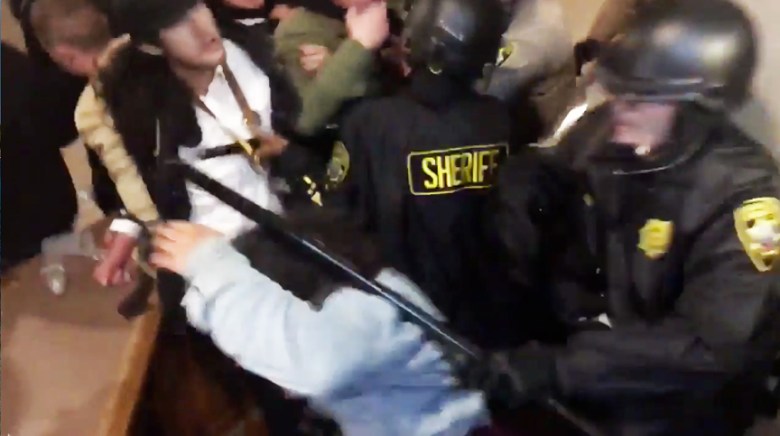 Una captura de pantalla de la fotógrafa de The Guardsman, Natasha Dangond siendo golpeada por el ayudante del alguacil, Osha, durante la protesta del 6 de mayo en el ayuntamiento. Video por Cece Carpio.