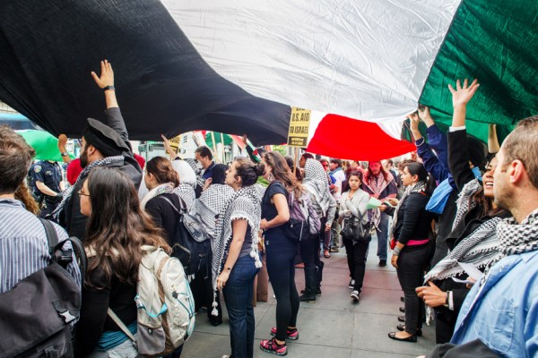 A crowd holds a Palestinian flag in front of the Israeli Consulate in San Francisco on July 7, 2014. Photo: El Tecolote Archives/Ramsey El-Qare