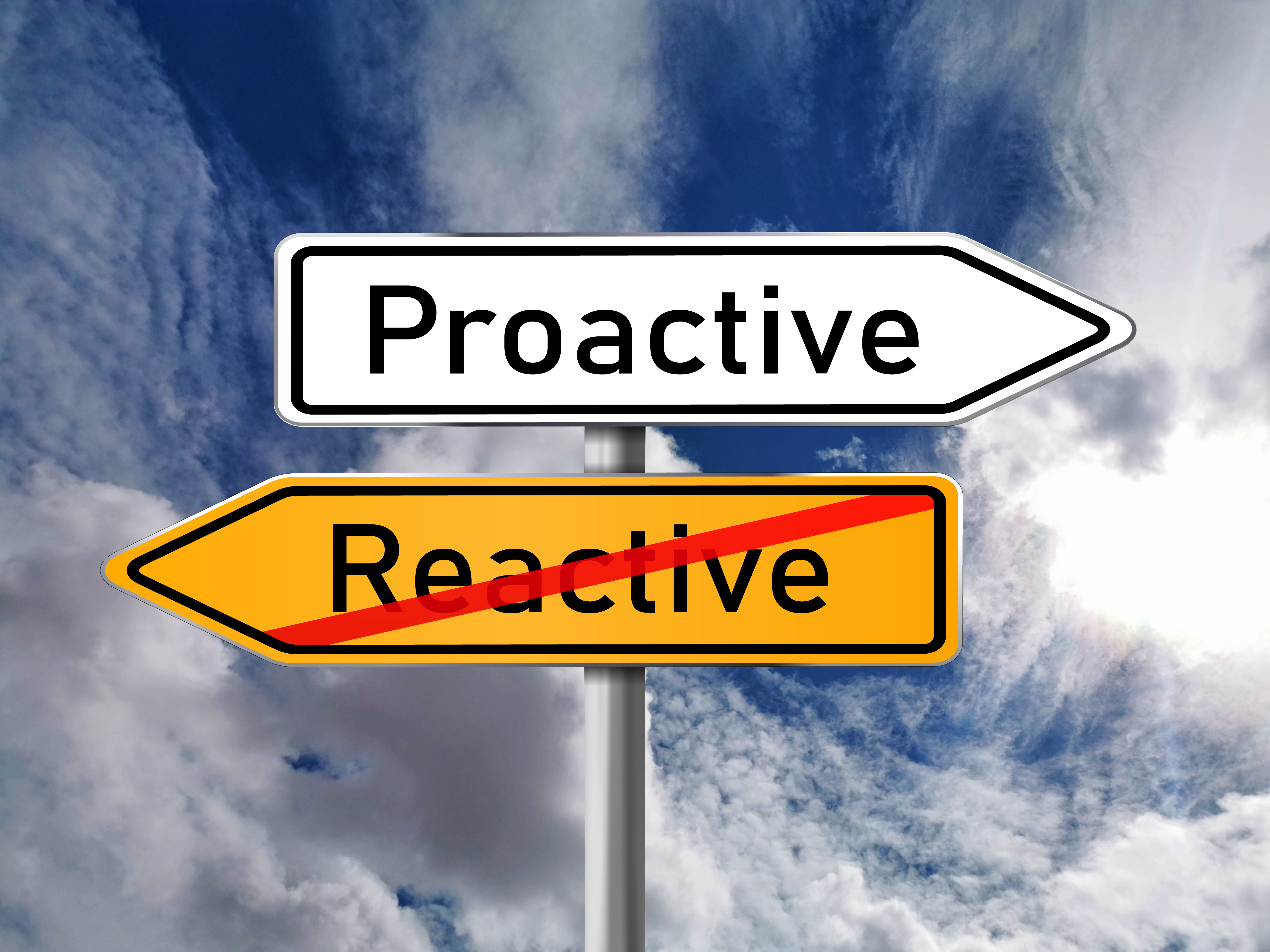 Two arrow-shaped signs pointing opposite directions with a sky background. The arrow which says Proactive is pointing to the right and the arrow which says Reactive is pointing to the left with a red line crossed through it..