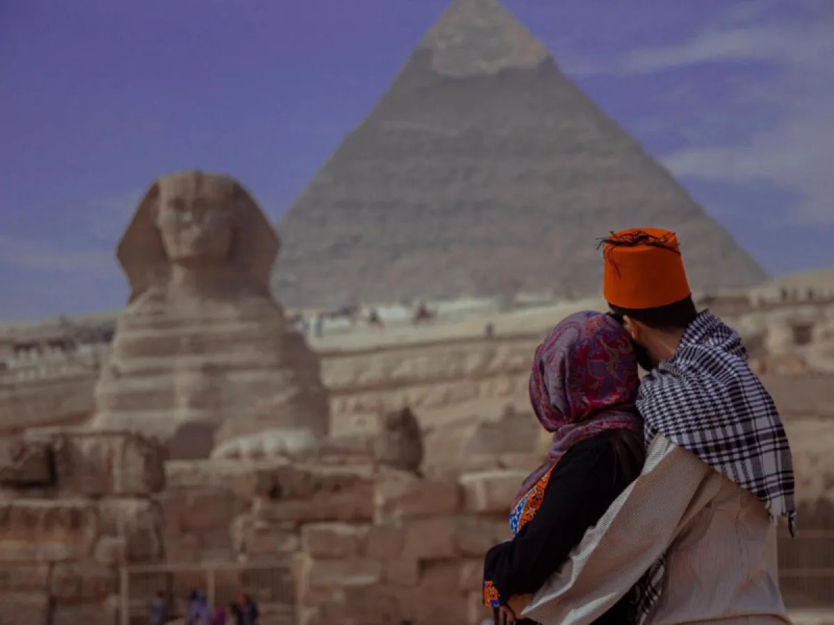 a man and woman in front of a pyramid