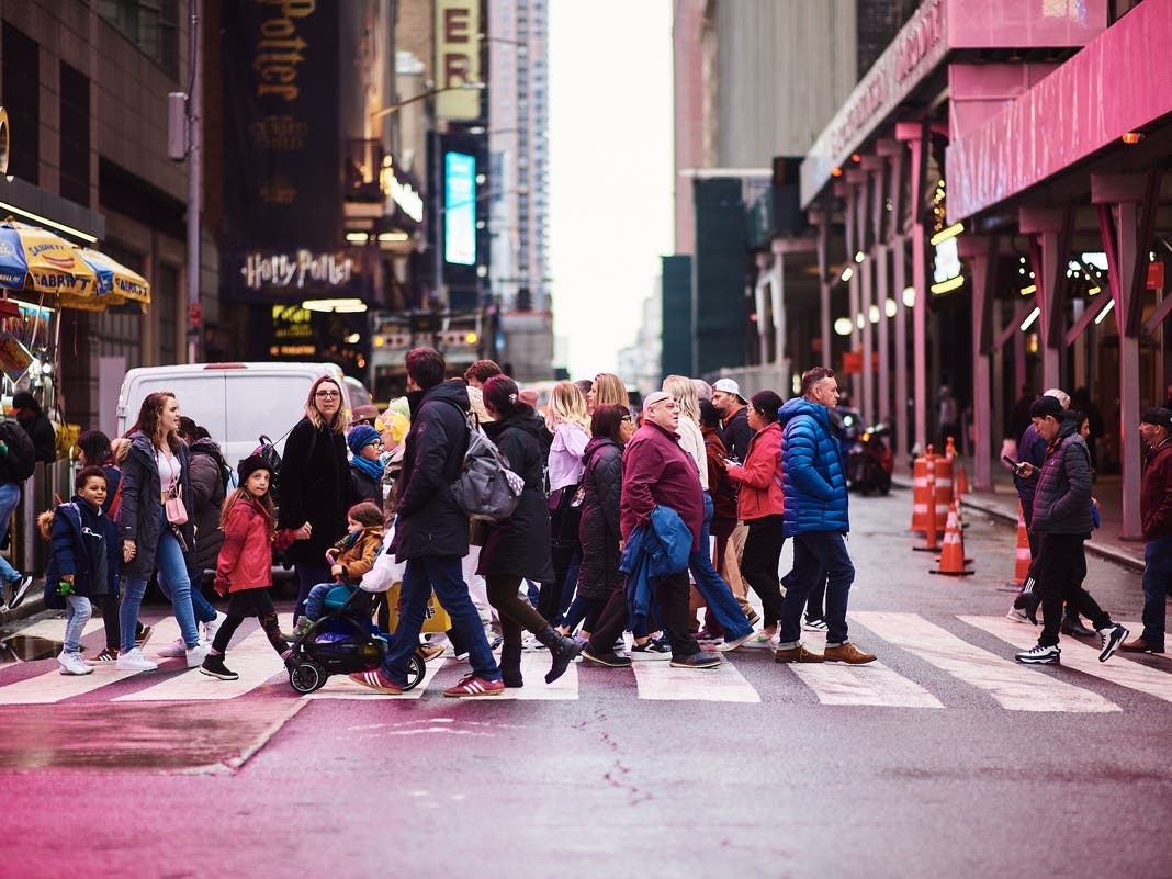 Pedestrians crossing in Times Square. NYC welcomed 65 million visitors last year.