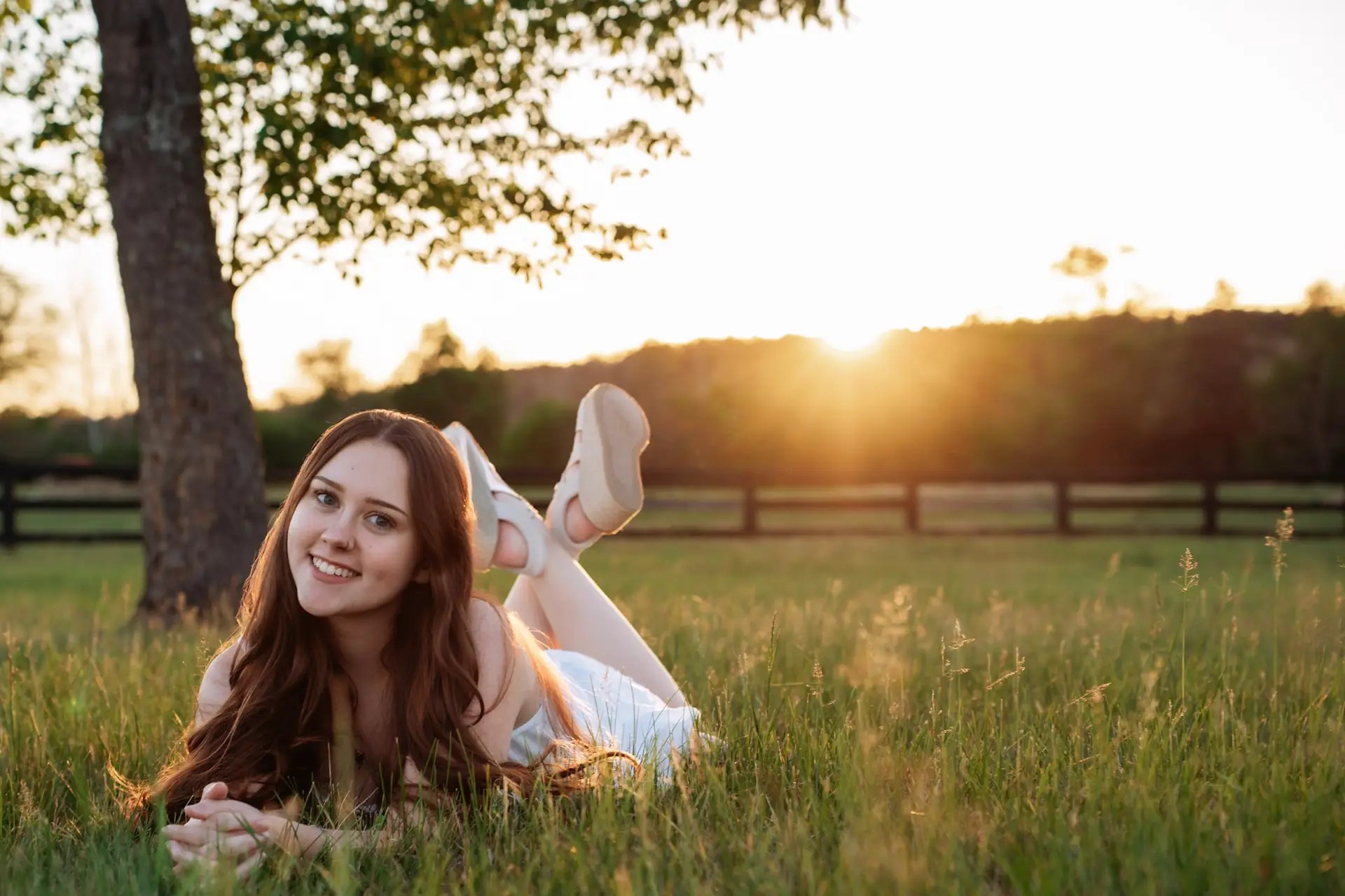 Senior girl sitting in a field at sunset during an outdoor photography session