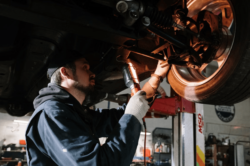 Technician inspecting a vehicle's suspension and brake components from underneath