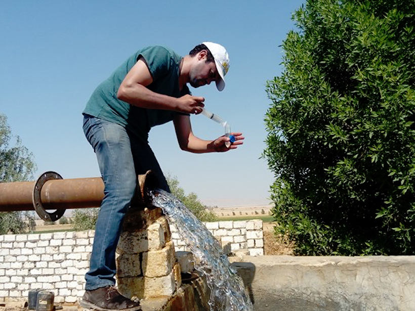 Man collects water from a pipe to put in a test tube.