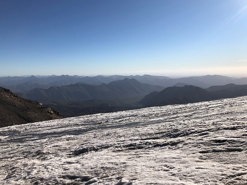 View from atop a glacier looking toward mountains on the horizon