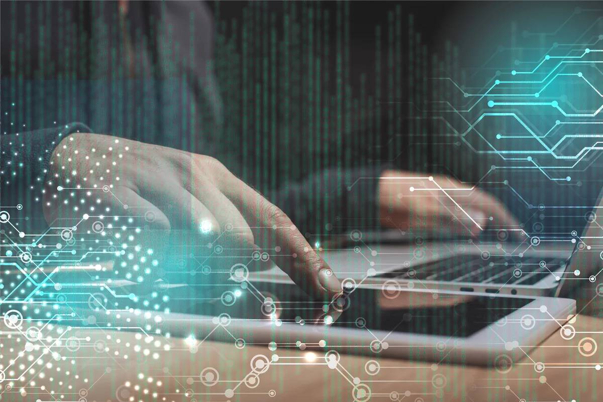 A person’s hands typing on a laptop keyboard with digital circuit and binary code graphics overlaying the image, symbolizing seamless integration within 800G Networks and the precision required for efficient fiber patching.