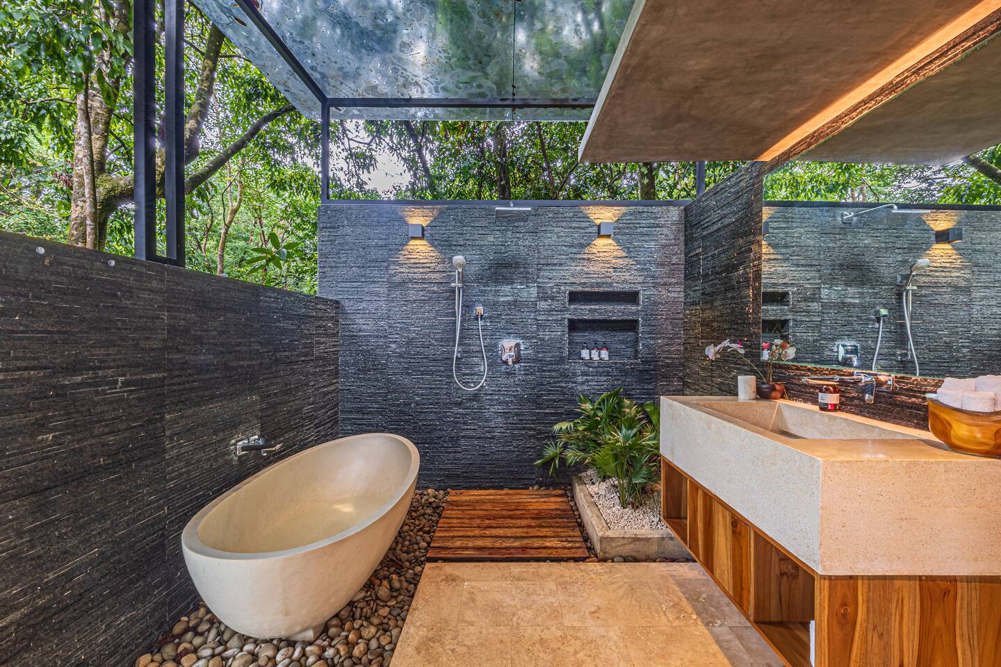 Open-air spa bathroom with stone bathtub, large windows, and jungle surroundings in a luxury villa near Dominical, Costa Rica.