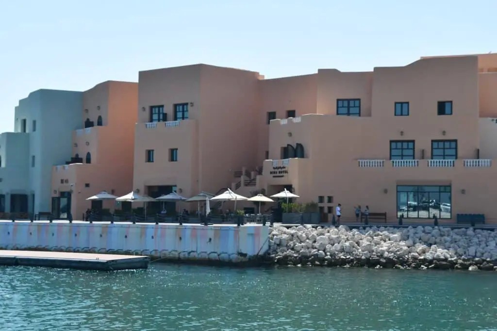 Edificios de estilo tradicional en Mina District, en el puerto antiguo de Doha . Se ve el mar, con terrazas y restaurantes al aire libre.