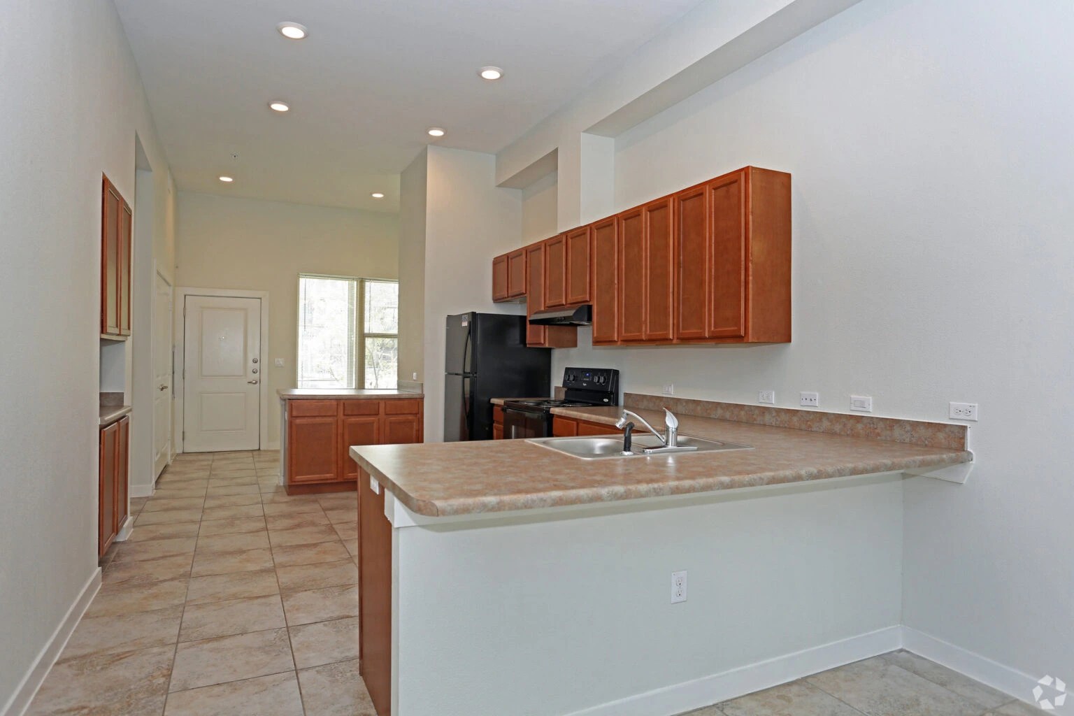Lakeline Station apartment kitchen with wood cabinetry and stainless steel appliances